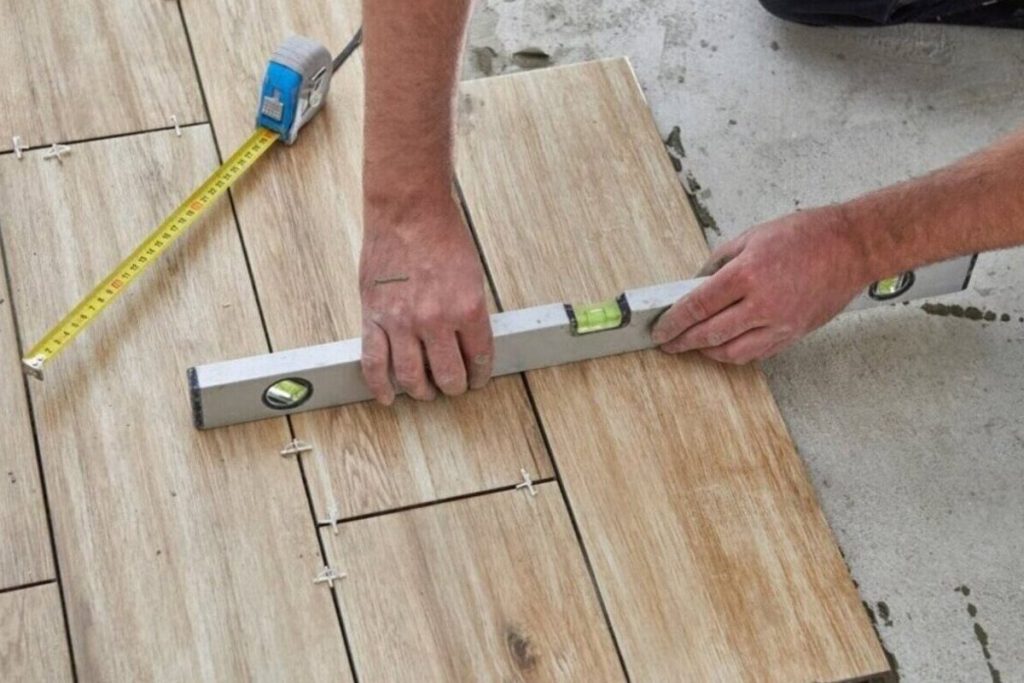 Installer measuring concrete floor flatness with a level and tape before flooring installation.